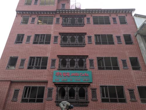 Un edificio alto de ladrillo rojo con un cartel. en Jhigu Casa, en Kirtipur