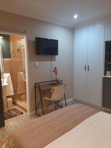 a bedroom with a bed and a desk and a shower at Strandloper Room in Cape Town