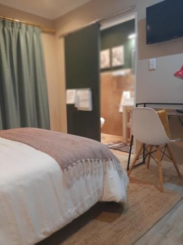 a bedroom with a bed and a desk and a television at Strandloper Room in Cape Town
