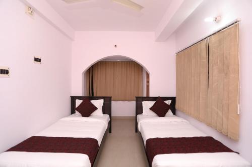 two beds in a room with white walls at Hotel O BORO MA GUEST HOUSE in Salt Lake City