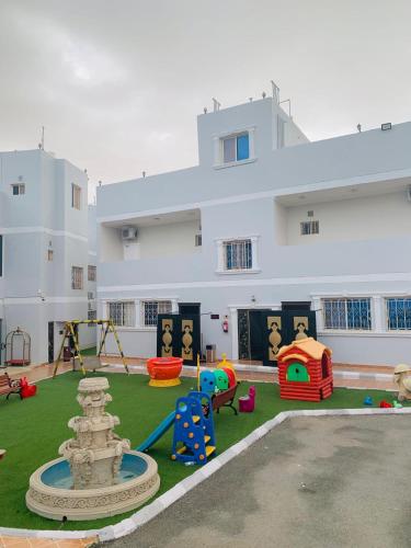 a large white building with a playground in a yard at شقق ارين المصيف in Al Hada