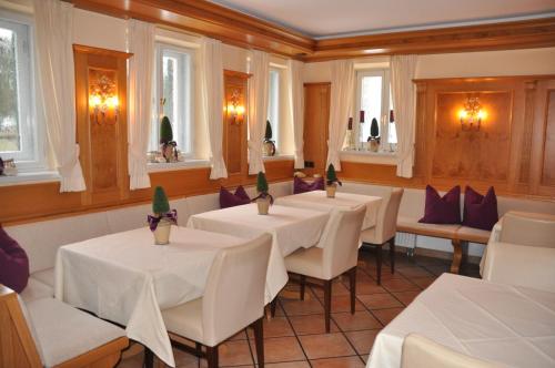 a restaurant with white tables and chairs and windows at Hotel Fischerhaus in Starnberg