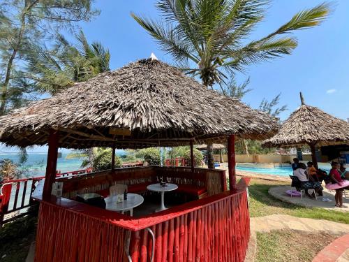 a restaurant with a table and a straw umbrella at Seabreeze apartments in Mombasa