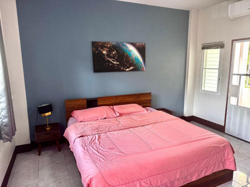 a bedroom with a bed with a pink blanket at พีเอส โฮม ฝาง in Ban Huai Ngu