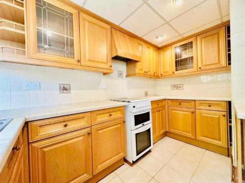 a kitchen with wooden cabinets and a white stove top oven at Castle Donington 5 Bed House 2 Baths Near EMA And Donington Park in Castle Donington