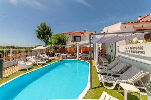 a swimming pool with chaises and chairs next to a building at 4Ever Palace Design&Nature in Alcácer do Sal
