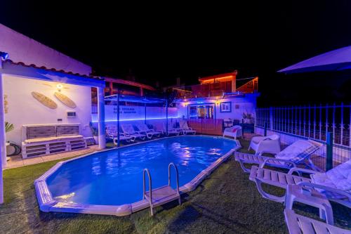 a swimming pool at night with chairs and an umbrella at 4Ever Palace Design&Nature in Alcácer do Sal