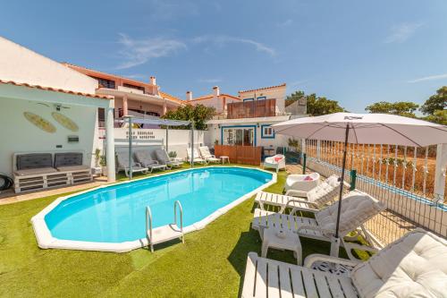 a swimming pool with chairs and an umbrella next to a house at 4Ever Palace Design&Nature in Alcácer do Sal