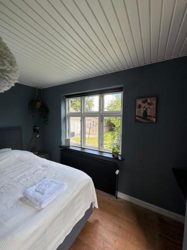 a bedroom with a white bed and a window at Modern Retreat close to everything in Djursland in Grenå