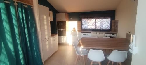 Una cocina con una mesa de madera y sillas blancas. en Le Pigeonnier, en Puygouzon-et-Montsalvy
