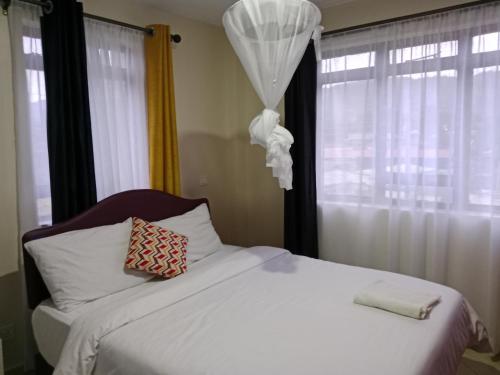 a bedroom with a white bed and a window at Mimos 2 BR Machakos in Machakos