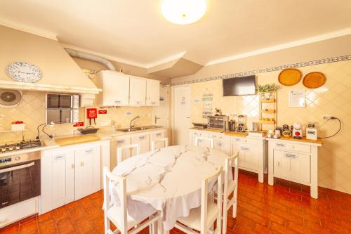a kitchen with white cabinets and a table and chairs at 4Ever Palace Design&Nature in Alcácer do Sal