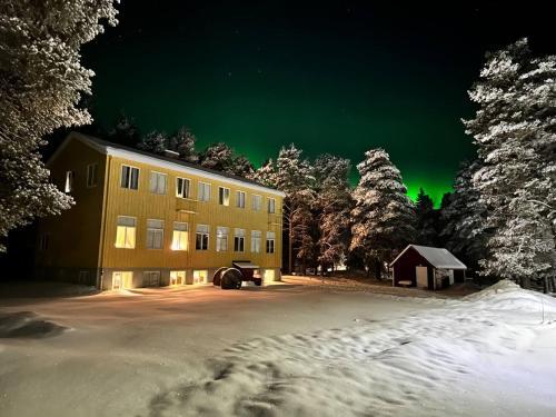 a building in the snow with a green sky at Skolan - Boende Vindelälven in Gargnäs