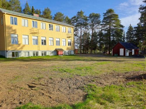 a large yellow building with a red barn and a field at Skolan - Boende Vindelälven in Gargnäs