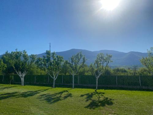 a field with trees and a fence with mountains in the background at Little Joy Lodge , Loč Mala Radost in Bihać