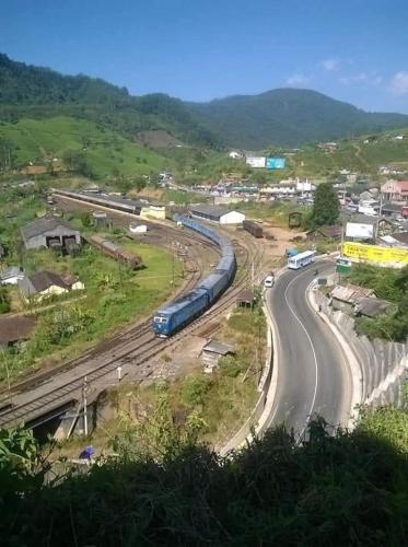 a train traveling down a road next to a street at Garden View's Rest in Nuwara Eliya