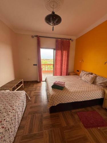 Un dormitorio con dos camas y una gran ventana. en chez JM saida, en Ourika