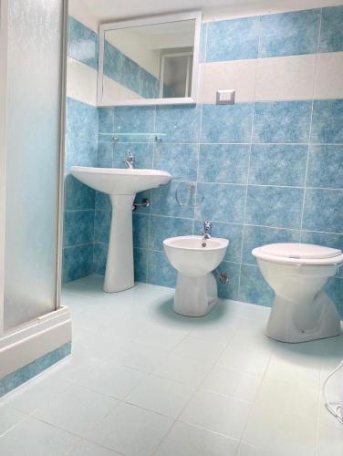 a blue tiled bathroom with a sink and a toilet at La Dolce Sosta in Luras