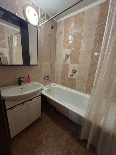 a bathroom with a sink and a bath tub and a mirror at УЮТ 2-комнатная квартира в центре in Petropavlovsk
