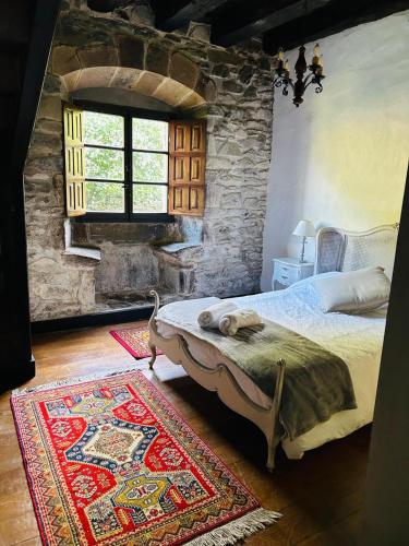 a bedroom with a bed and a stone wall at Goikitxe Etxea in Goizueta