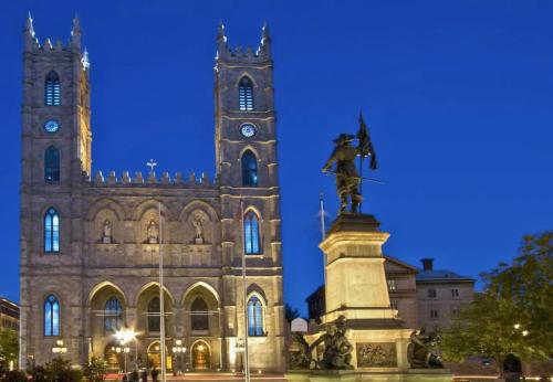 a statue in front of a building with a clock tower at LiV MTL Main in Montréal