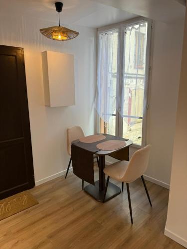 a dining room with a table and chairs and a window at Cocon Écorce & Mandarine in Joigny