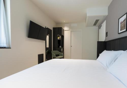 a bedroom with a large white bed and a chair at Hotel Stelvio Tirano in Tirano