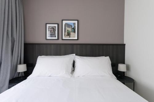 a bedroom with a white bed with two pictures on the wall at Hotel Stelvio Tirano in Tirano