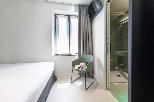 a bedroom with a bed and a chair and a shower at Hotel Stelvio Tirano in Tirano