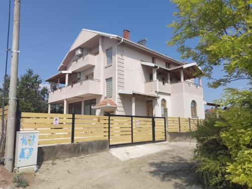 a large white house with a wooden fence at Lazarevski Apartments Kumanovo in Kumanovo
