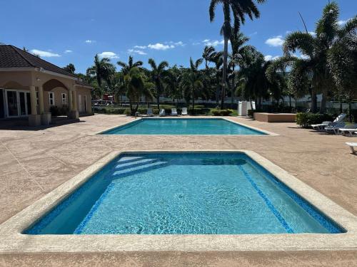 two swimming pools in a yard with palm trees at Spacious 3 Bed Home, Pool & Gym Access in Steer Town