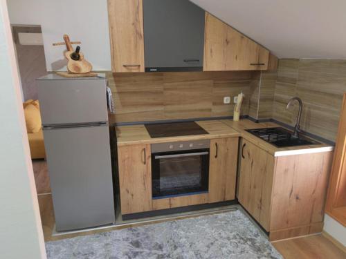 a small kitchen with wooden cabinets and a refrigerator at Lazarevski Apartments Kumanovo in Kumanovo