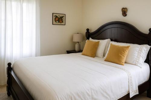 a bedroom with a large bed with white sheets and yellow pillows at Spacious 3 Bed Home, Pool & Gym Access in Steer Town