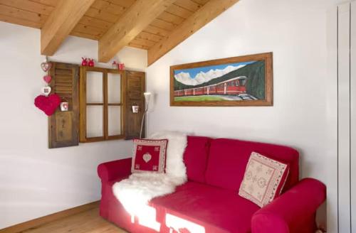 a living room with a red couch and a picture of a train at B&B Ca' La Vedescia in Teglio