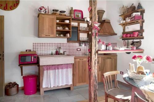 a kitchen with wooden cabinets and a pink microwave at B&B Ca' La Vedescia in Teglio