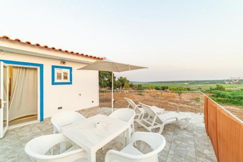a patio with a table and chairs and an umbrella at 4Ever Palace Design&Nature in Alcácer do Sal