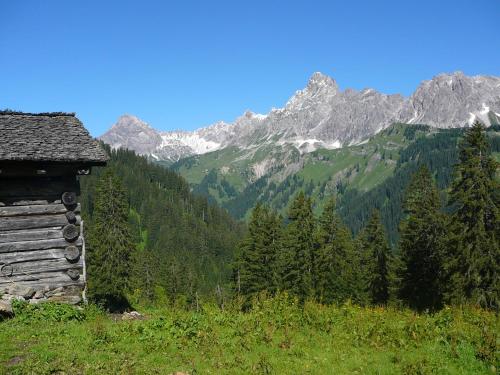 an old cabin on a hill with mountains in the background at Ferienwohnung Amann in Vandans
