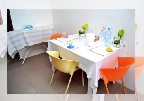 a white table with orange chairs in a room at Chez Ouly in Dakar