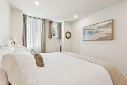 a white bedroom with a large white bed and a window at Casa Riviera - Boutique Apartments in Downtown Santa Barbara in Santa Barbara
