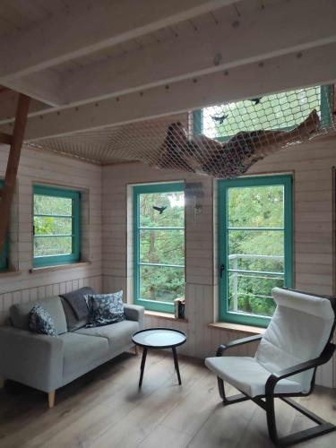 sala de estar con sofá, mesa y ventanas en Węgiełek Treehouse Little Barn, en Kazimierz Dolny