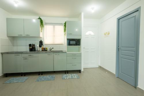 a kitchen with white cabinets and a blue door at Luxury cozy Apartment in Koolbaai