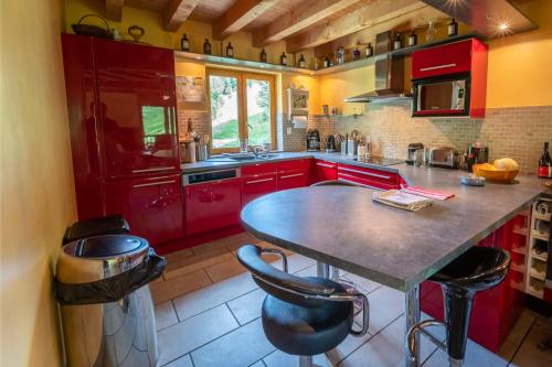 a kitchen with red cabinets and a table with stools at Magnifique chalet à 3km PEYRAGUDES PYRENEES LUCHON in Gouaux-de-Larboust
