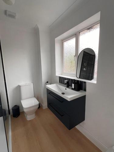 a bathroom with a sink and a toilet and a window at La CAZA Guest House in Royston