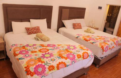 two beds in a hotel room with flowers at Kay Pacha Wellness Place Eco in Ayacucho