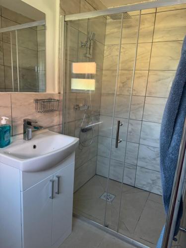 a bathroom with a shower with a sink and a mirror at Newly built studio apartment in Manchester