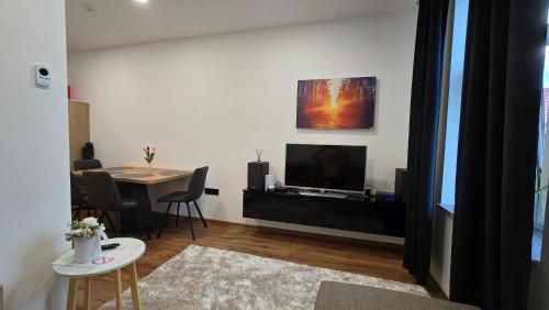 a living room with a television and a table with chairs at Apartment Lovro in Ivanec