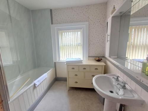 a white bathroom with a tub and a sink at Lyndale Guesthouse in Pateley Bridge