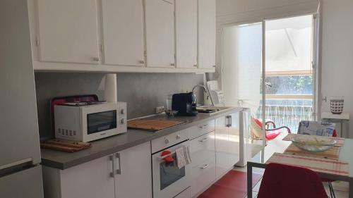une cuisine avec des armoires blanches et un micro-ondes dans l'établissement CANNES Un pied dans l'eau, Un pied en ville, à Cannes