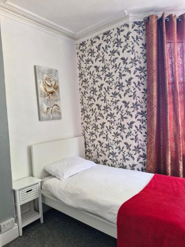 a bedroom with a bed with a floral headboard at Victoria Guest House in Bedford