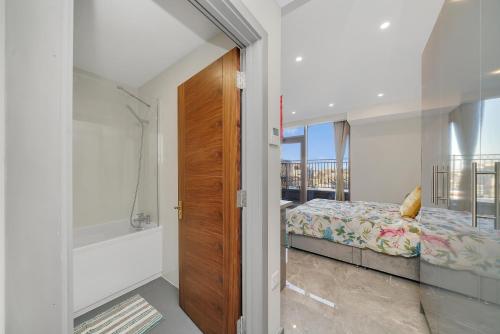 a bedroom with a bed and a bathroom with a balcony at Studio with Balcony Godino Hotel Ilford in Ilford